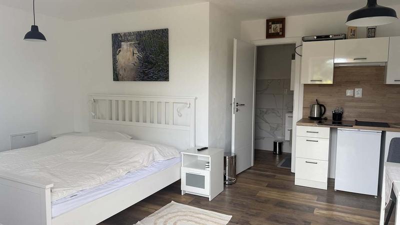 Ložnice apartmánu 2 s manželskou postelí, vzadu kuchyňský kout