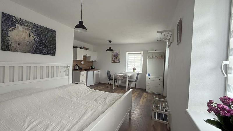 Apartmán 2: postel a jídelní kout u okna