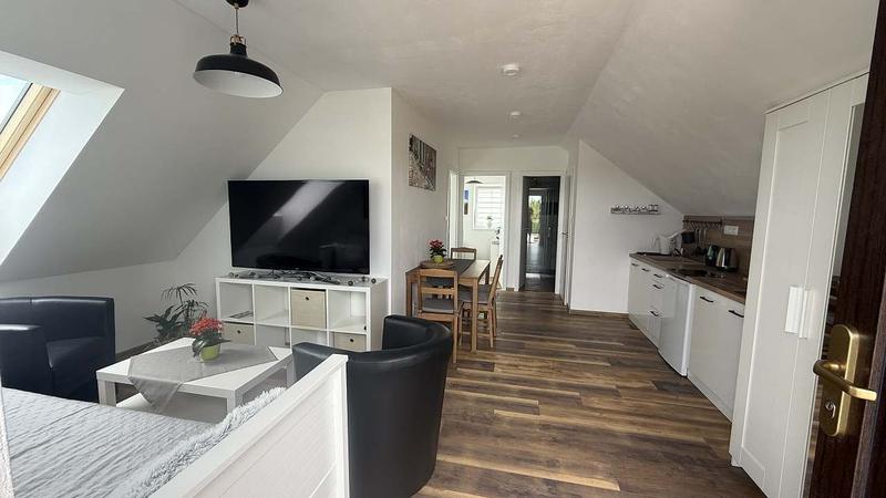 Obývací pokoj apartmánu 3 s televizí a kuchyňským koutem v pozadí